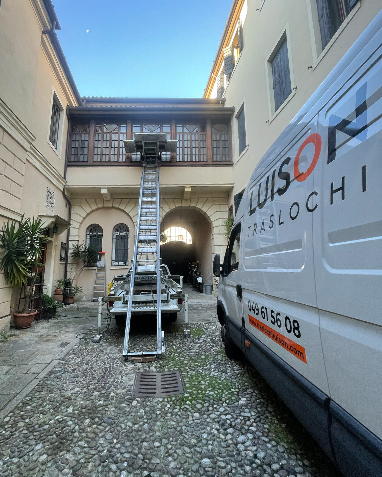 Trasloco Luison a Padova: piattaforma aerea e furgone al lavoro in un cortile